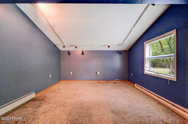 carpeted empty room with lofted ceiling, baseboard heating, and rail lighting