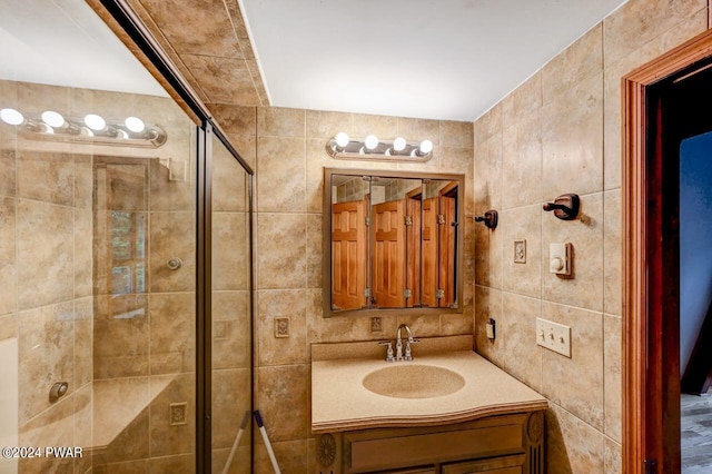 bathroom with an enclosed shower, vanity, and tile walls