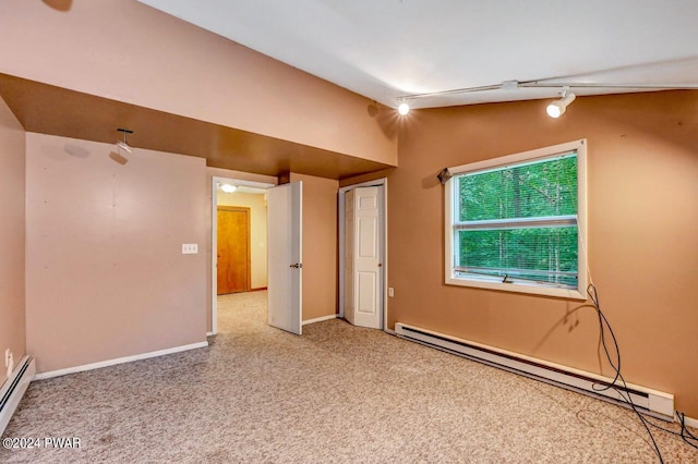 carpeted spare room with rail lighting, lofted ceiling, and a baseboard heating unit