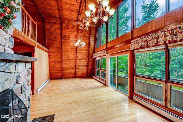 unfurnished living room featuring beam ceiling, a baseboard radiator, wooden ceiling, a high ceiling, and a stone fireplace