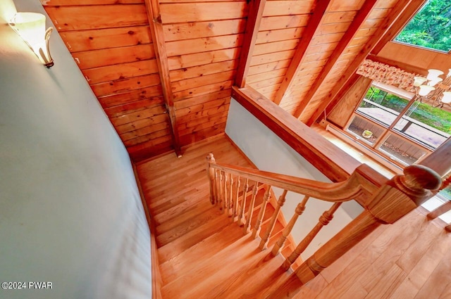 stairs featuring hardwood / wood-style floors, lofted ceiling with beams, wood walls, and wooden ceiling