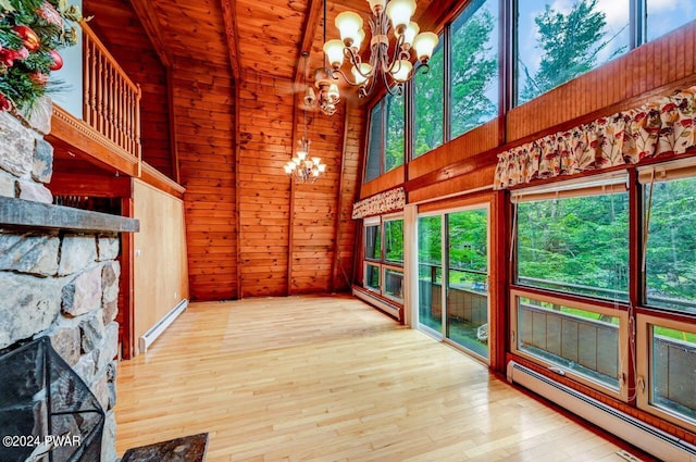 unfurnished sunroom featuring a fireplace, an inviting chandelier, wood ceiling, and a baseboard heating unit