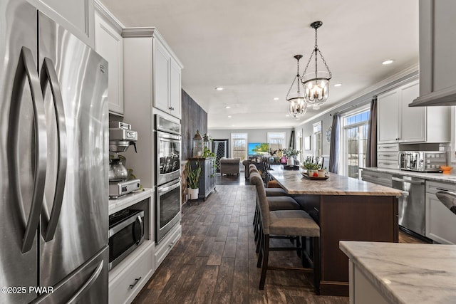 kitchen featuring an inviting chandelier, appliances with stainless steel finishes, a kitchen island, and white cabinets