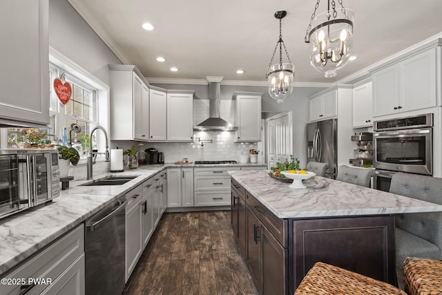 kitchen with appliances with stainless steel finishes, dark hardwood / wood-style floors, sink, a chandelier, and wall chimney exhaust hood