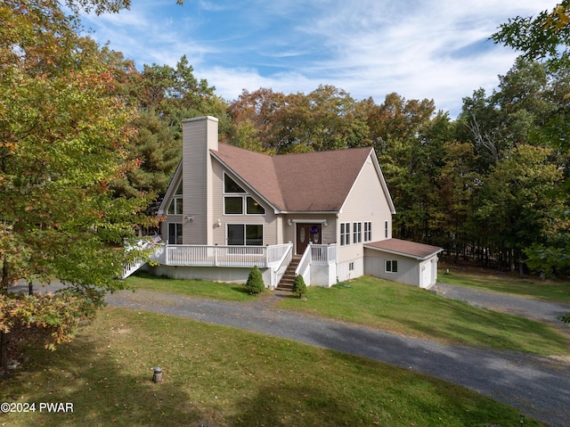 view of front of property with a deck, an outdoor structure, and a front lawn