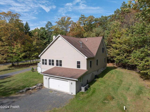 view of property exterior with a lawn, central air condition unit, and a garage