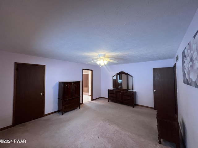 unfurnished bedroom with a textured ceiling, light colored carpet, and ceiling fan