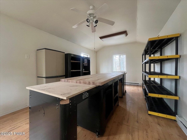 kitchen with light wood finished floors, a center island, ceiling fan, vaulted ceiling, and baseboard heating