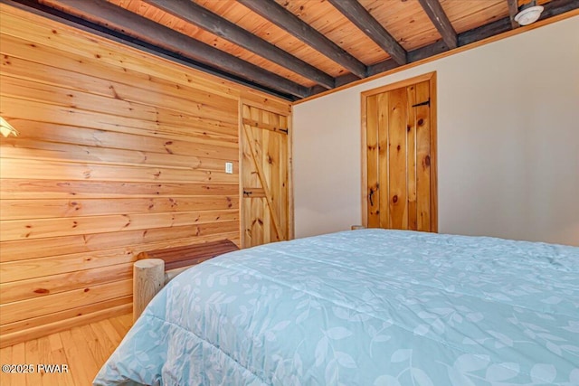 bedroom with beam ceiling, wooden walls, and wooden ceiling