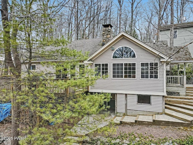 back of house with a shingled roof, fence, and a chimney