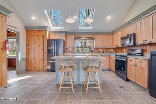 kitchen featuring vaulted ceiling with skylight, light brown cabinets, stainless steel appliances, and light countertops