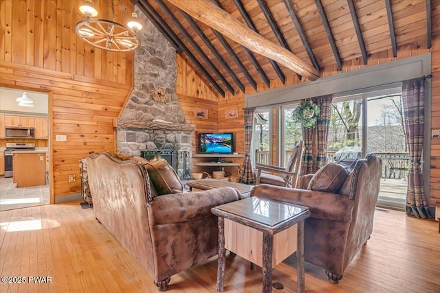 living room featuring beam ceiling, a stone fireplace, wood walls, light wood finished floors, and wood ceiling