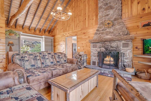 living area featuring wood finished floors, a stone fireplace, wood ceiling, wood walls, and beamed ceiling