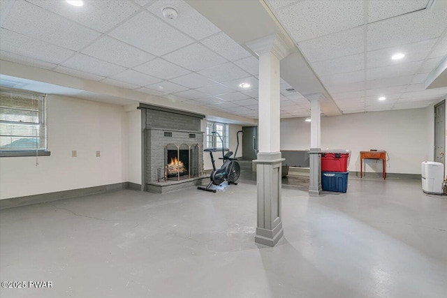 basement featuring a brick fireplace, recessed lighting, baseboards, and a drop ceiling