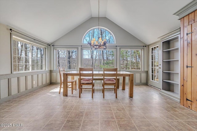 unfurnished dining area featuring a notable chandelier, built in shelves, and high vaulted ceiling