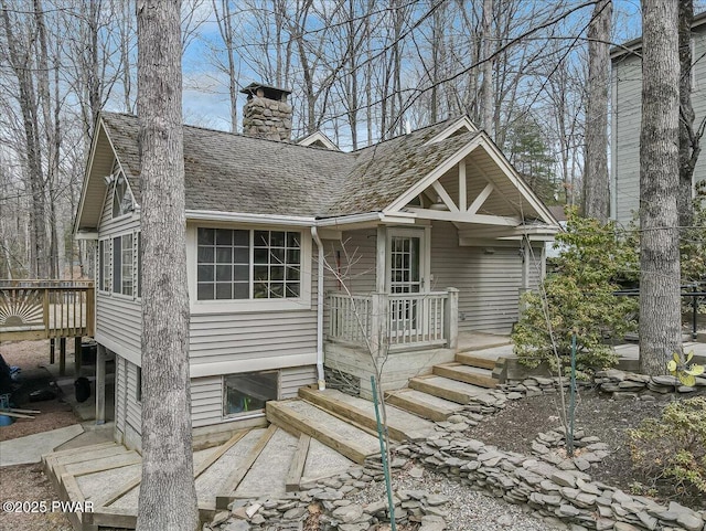 view of front of home with a shingled roof and a chimney