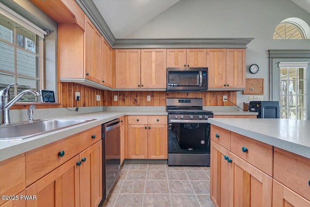 kitchen with light brown cabinetry, light countertops, lofted ceiling, stainless steel appliances, and a sink