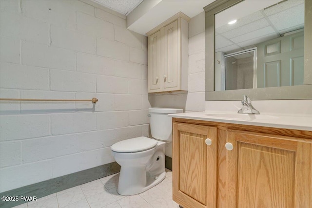 full bath with concrete block wall, vanity, a shower stall, and toilet