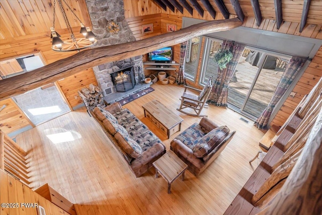 living room with hardwood / wood-style floors, wooden walls, a notable chandelier, and a fireplace