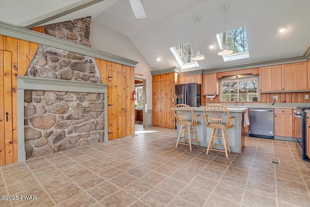 kitchen with lofted ceiling with skylight, stainless steel dishwasher, a center island, a breakfast bar area, and light countertops