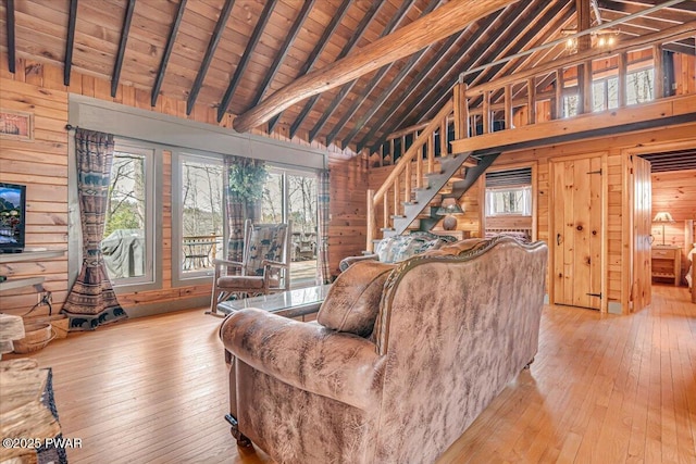 living area with lofted ceiling with beams, wood-type flooring, wood ceiling, and wood walls