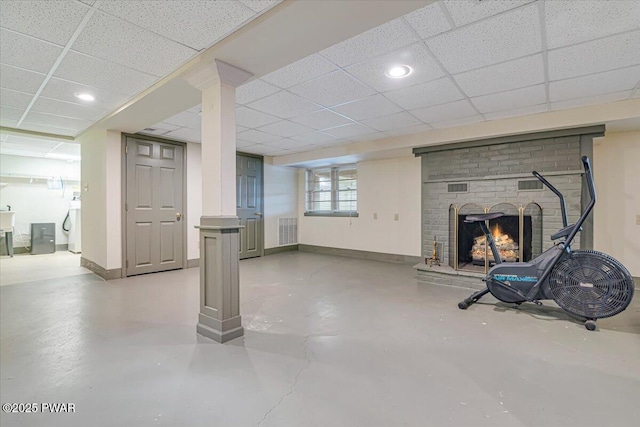 below grade area featuring visible vents, baseboards, washer / clothes dryer, a paneled ceiling, and a brick fireplace