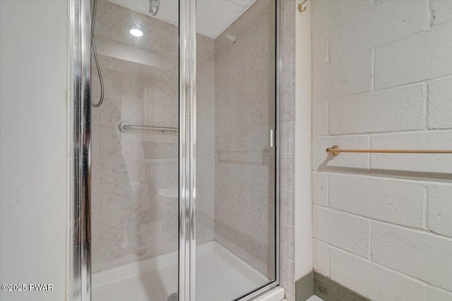 full bath with a shower stall and concrete block wall