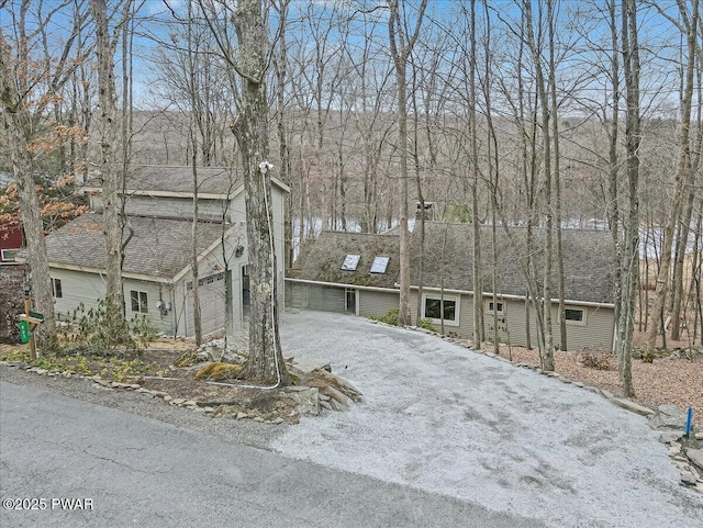 view of front facade with a garage, driveway, and a shingled roof