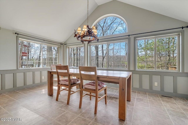 dining room with a chandelier, a decorative wall, high vaulted ceiling, and visible vents