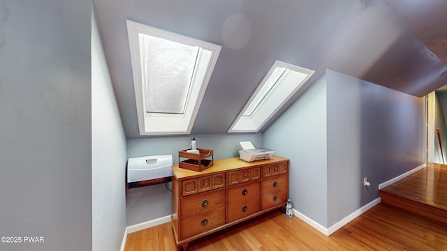 additional living space featuring light wood-type flooring and lofted ceiling with skylight