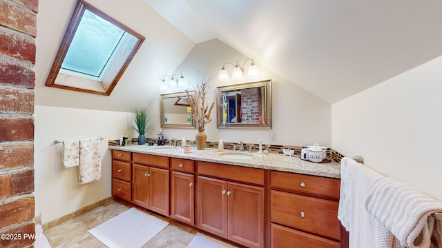 bathroom featuring vaulted ceiling with skylight and vanity