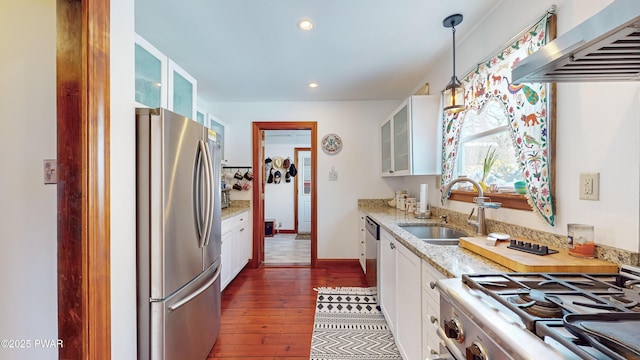 kitchen with range, white cabinetry, stainless steel refrigerator, pendant lighting, and wall chimney exhaust hood