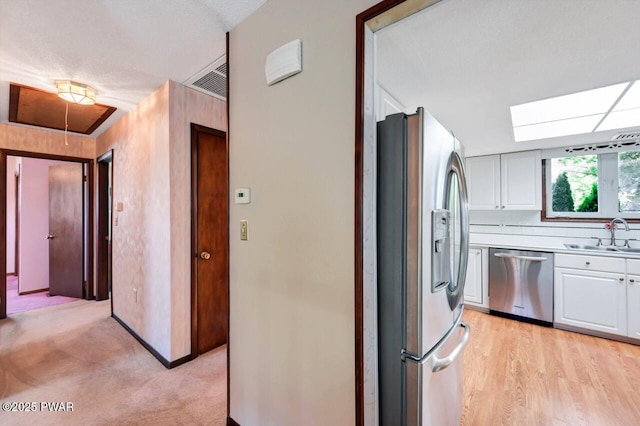 1528 Mount Cobb Rd, Jefferson Township, PA 18436 - kitchen featuring appliances with stainless steel finishes, white cabinets, light countertops, and a skylight