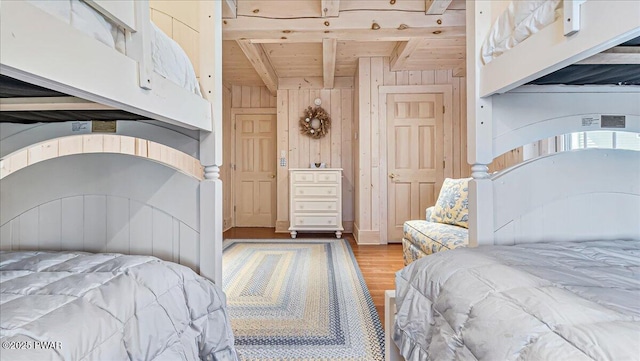 bedroom with wood ceiling, wood finished floors, wooden walls, and beamed ceiling