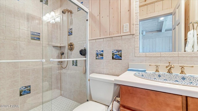 bathroom with vanity, toilet, tile walls, and a stall shower