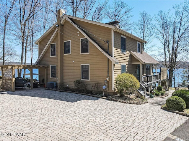 exterior space with decorative driveway, central AC, a chimney, and stairs