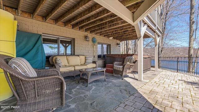 view of patio with a hot tub, a water view, fence, and an outdoor hangout area