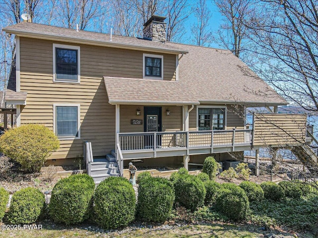 view of front of home featuring covered porch, a chimney, a shingled roof, and central air condition unit