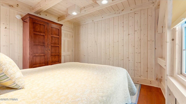 bedroom featuring wood walls, wood finished floors, wooden ceiling, and beamed ceiling