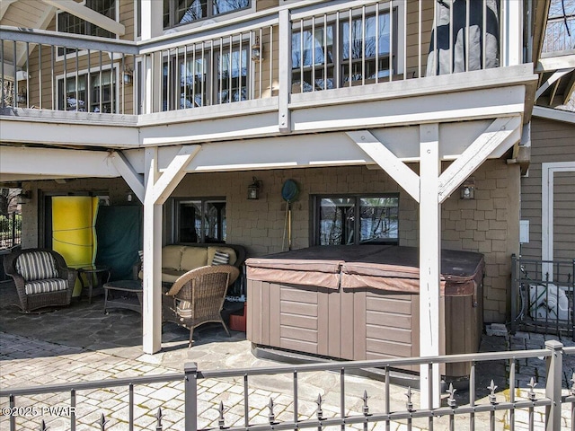 view of patio / terrace with a hot tub, fence private yard, and a balcony