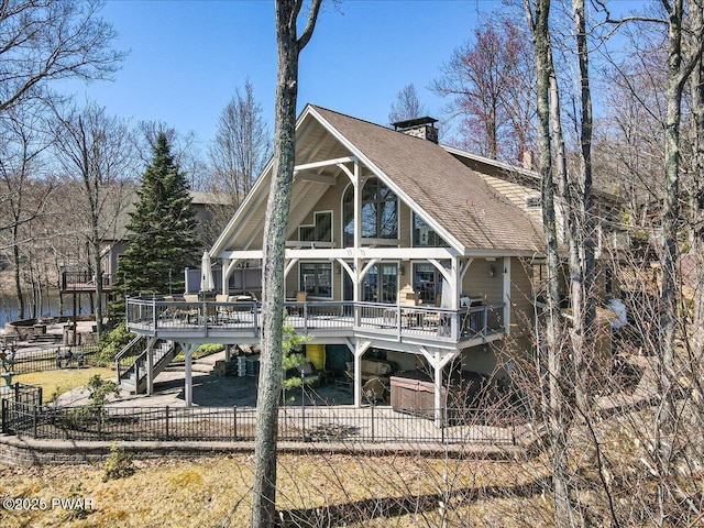 rear view of house with a wooden deck, a fenced backyard, a chimney, a shingled roof, and stairway