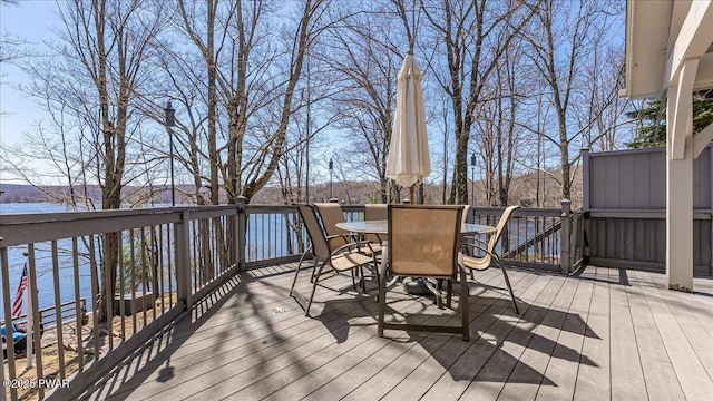 wooden deck with a water view and outdoor dining space
