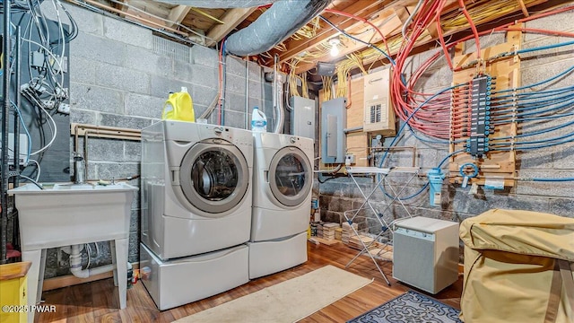 clothes washing area with laundry area, washing machine and dryer, wood finished floors, and electric panel