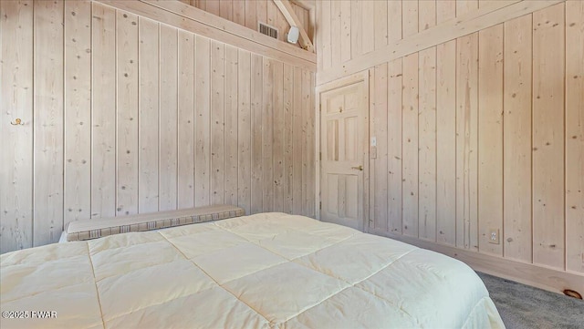 carpeted bedroom with wooden walls and visible vents