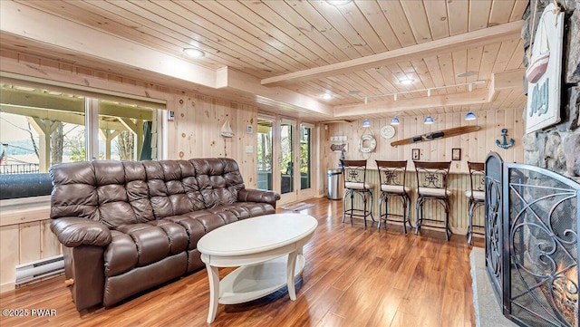 living area featuring wooden walls, wooden ceiling, baseboard heating, and light wood finished floors