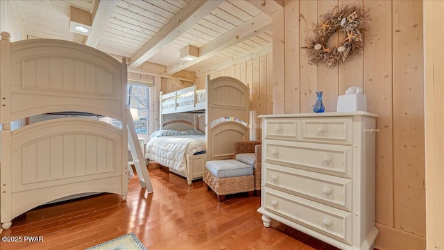 bedroom with wooden walls, beam ceiling, wood ceiling, and hardwood / wood-style floors