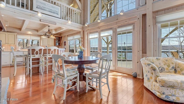 dining space with a wealth of natural light, beam ceiling, and light wood-type flooring