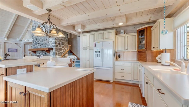 kitchen featuring a sink, light wood-style flooring, white fridge with ice dispenser, and wooden ceiling