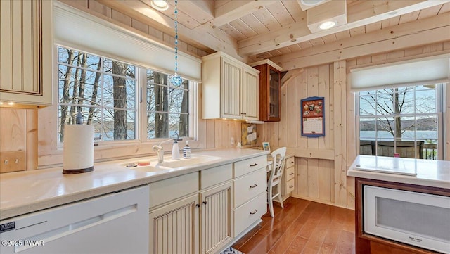 kitchen with beam ceiling, wood finished floors, white appliances, wooden ceiling, and a sink