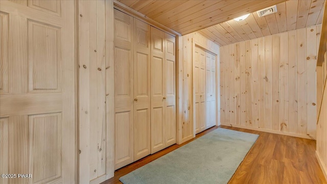 interior space with visible vents, wood finished floors, wooden walls, and wooden ceiling